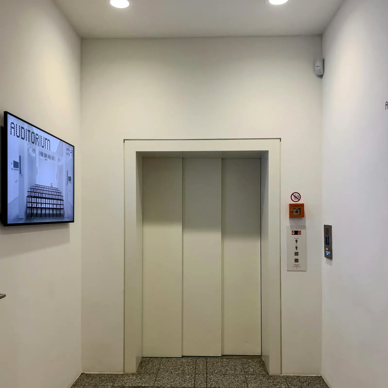 Lift ajtaja egy világos lépcsőházi előtérben